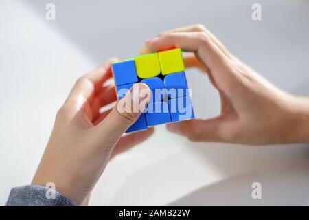 Perm, Russia, September 28 2019: Rubik's cube in the hands of a boy. The child holds a Rubik's cube on a light background, playing with it. Close up. Stock Photo