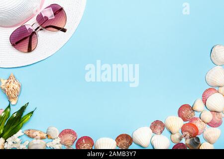 Summer hat, glasses, shells on a blue background. The concept of vacation, sea, travel. Copy space. Stock Photo