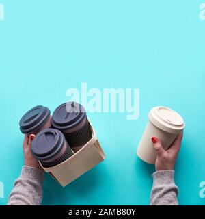 Assorted bamboo travel reusable coffee or tea cups or mags with silicone insulation on green mint background. Hand hold several mugs in box. Eco frien Stock Photo