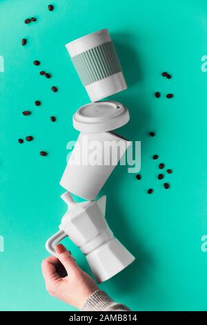 Balancing zero waste coffee pyramid in female hands on green mint background. Ceramic espresso coffee maker and eco friendly reusable bamboo coffee mu Stock Photo