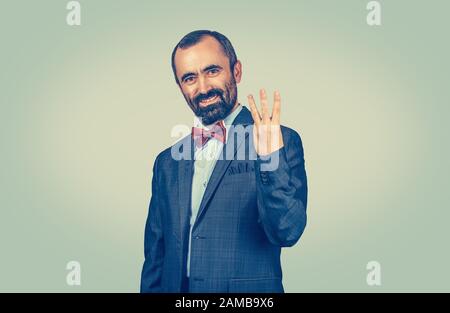 Bearded man, employee giving three fingers gesture with hand isolated on green yellow uniform background. Facial expression feeling symbol body langua Stock Photo