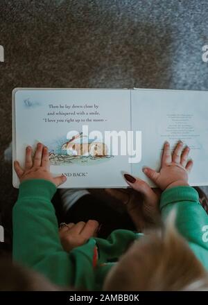 Young child reading with their mum Stock Photo