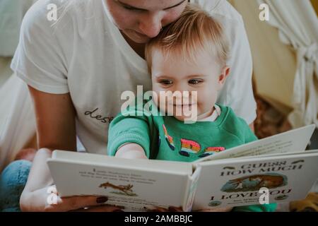 Young child reading with their mum Stock Photo
