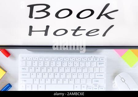 Book Hotel, text on the computer monitor. View from above. Desk with keyboard, mouse, colorful sticky notes, Concept of booking hotels around the worl Stock Photo
