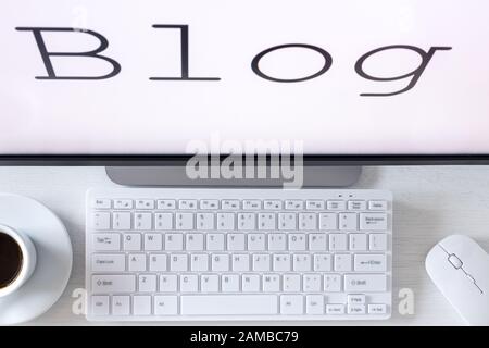 text displayed on the monitor, Blog. A desk with a computer keyboard and a cup of coffee. The concept of running your own website for the internet Stock Photo
