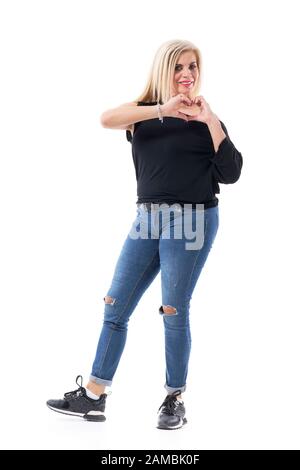 Mother's love. Middle age beautiful casual woman showing heart hand symbol and looking at camera. Full body length isolated on white background. Stock Photo