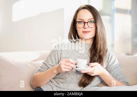 Portrait of smiling young woman starting her day with a cup of coffee. Stock Photo