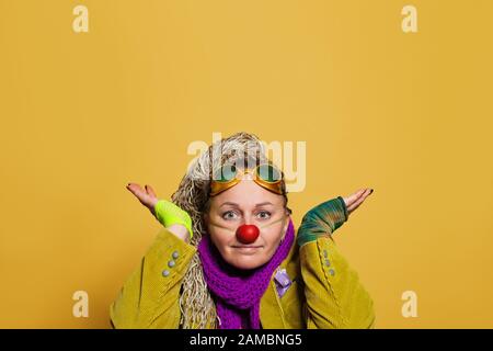 Female artist in clown costume on bright yellow background Stock Photo