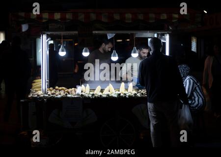 Boiled corn on the counter. A boiler with water in it. Egypt is boiled here. Photo was taken in the evening. A man who buys boiled corn. Stock Photo