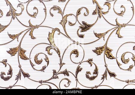 White porcelain tiles with a gold floral ornament. Ceramic tiles with volumetric golden pattern. Stock Photo