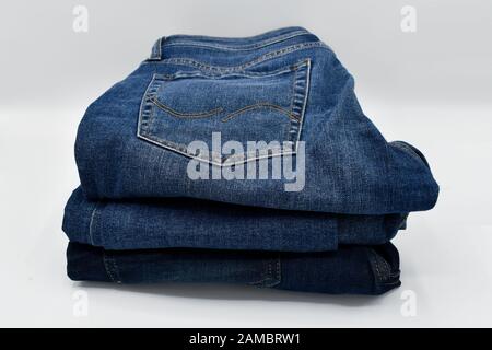 A pile of folded blue skinny jeans on a white background Stock Photo