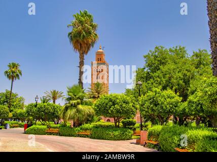 Koutoubia Mosque minaret at medina quarter of Marrakesh, Morocco. There is beautiful green garden with palms. Blue sky is in the background. Stock Photo