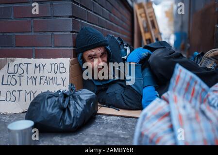 Bearded beggar sleeping on city street Stock Photo
