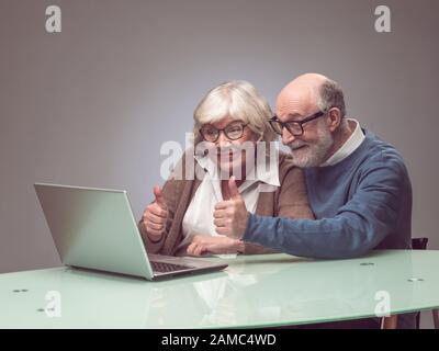 Senior couple using laptop together and smiling Stock Photo