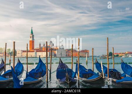 Gondolas moored by Saint Mark square with San Giorgio di Maggiore church on background in Venice, Italy during sunrise Stock Photo