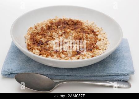 White bowl of hot oatmeal cereal with cinnamon garnish on white background Stock Photo