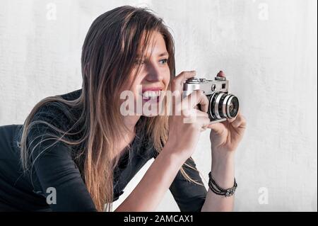 Stylish young girl photographer taking photos with a retro camera Stock Photo