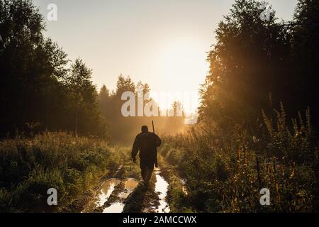 Summer hunting at sunrise. Hunter moving With Shotgun and Looking For Prey Stock Photo