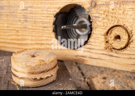 Wood hole saw and raw board. Making holes in raw wood. Place - carpentry workshop. Stock Photo