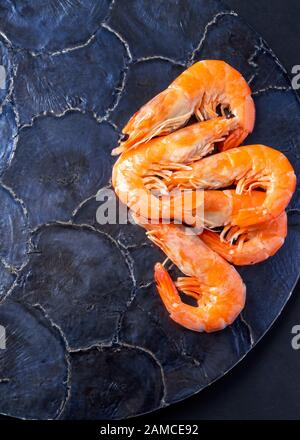 vertical image of group of cooked king prawns on a blue shell plate background copy space vertical image of group of cooked king prawns on a blue shell plate background copy space