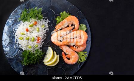 group of cooked king prawns on a blue shell plate background  with vegetables copy space Stock Photo