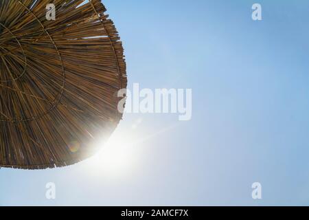 Sun umbrella against blue sky and sunlight. Summer vacation concept with copy space.