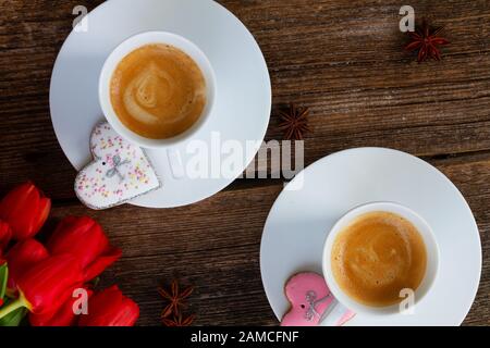 Two cups of Valentines day brewed coffee with fresh red tulips and gift box on wood, top view Stock Photo