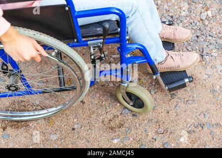 Legs feet handicap woman in wheelchair wheel on road in hospital park waiting for patient services. Unrecognizable paralyzed girl in invalid chair for disabled people outdoors. Rehabilitation concept Stock Photo
