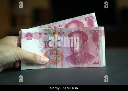 Hand holding a pile of 100 Chinese yuan bank notes. China currency concept. Stock Photo