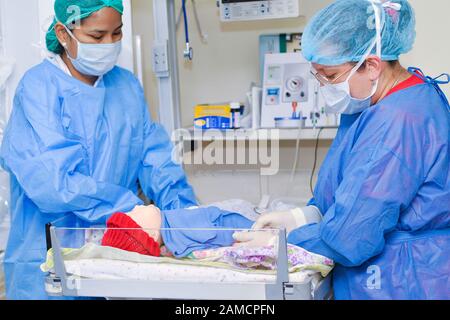 Doctors performing insertion of intravenous line on baby doll simulator.  Children Hospital. Guayaquil.  Ecuador Stock Photo
