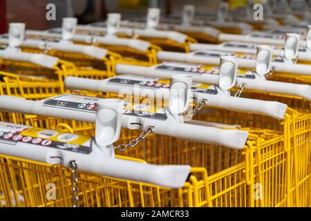 Rows of yellow branded shopping trolleys (carts) at a supermarket in France. Stock Photo