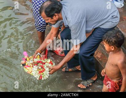 KOLKATA,WEST BENGAL/INDIA-MARCH 20 2018:A Hindu devotee places a floral offering into the waters of the Hooghly river,at one of the many ghats in Kolk Stock Photo