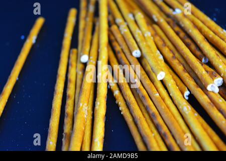 Tasty and salted straws with salt made from flour, sneking scattered on a black plastic background. Stock Photo