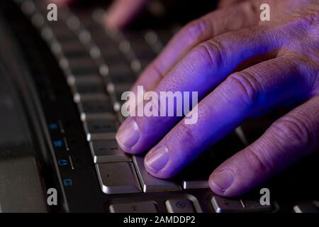 A man works at a computer. Hands of a man on the keyboard close-up. Programmer or hacker. Soft focus Stock Photo