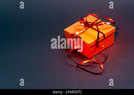 Gift box with red ribbon on a gray background. Red backlight Stock Photo