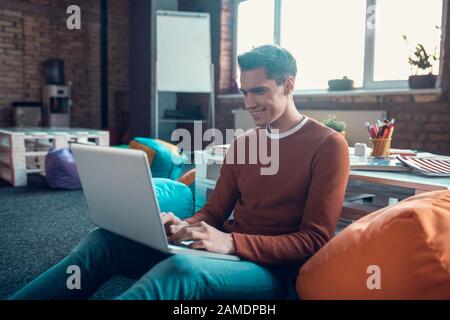 Cheerful handsome freelancer feeling good while working at home Stock Photo