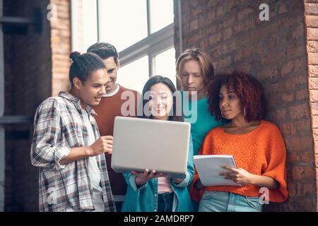 Students discussing and making notes while watching webinar Stock Photo