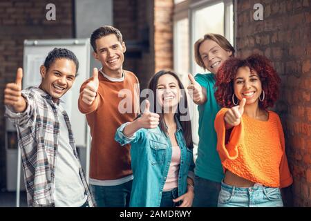 Students showing thumbs up while feeling good after studying Stock Photo