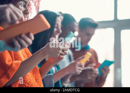 Students holding colorful smartphones while having break from study Stock Photo