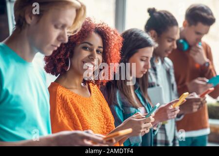 Student smiling standing near friends and using social media Stock Photo