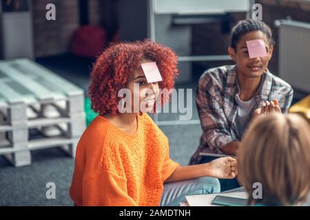 Curly mulatto student guessing word while playing game with best friends Stock Photo
