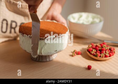 Man's hand levels cream on cake, cake decor. Making Sponge cake process. Stock Photo