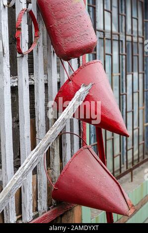 Wall mounted fire shield with fire fighting tools. Cone buckets and fire extinguisher. Side view. Selective focus. Without people. Vertical Stock Photo