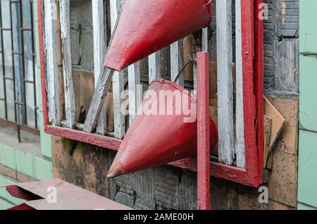 Two cone buckets hang on a fire shield. Side view of an old fire shield on the exterior wall of a building. Fire safety. Selective focus. Stock Photo