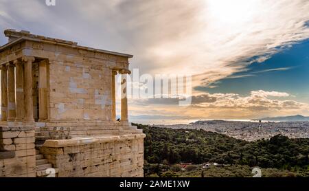 The Temple of Athena Nike, on the Acropolis of Athens, Greece, named after the Greek goddess Athena. Philopappos Hill and Piraeus is in the background Stock Photo