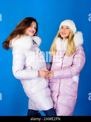 Women wear down jacket with furry hood. Girls smiling makeup faces