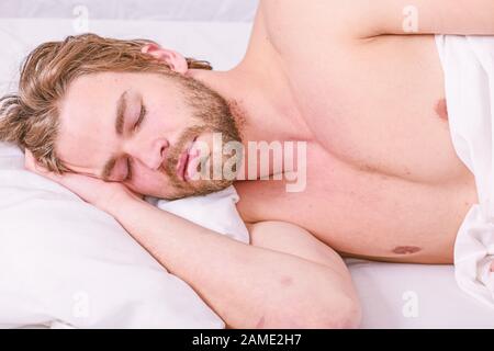 Man handsome guy lay in bed in morning. Tips on how to wake up feeling fresh and energetic. Morning routine tips to feel good all day. How to get up in morning feeling fresh. Late morning overslept. Stock Photo