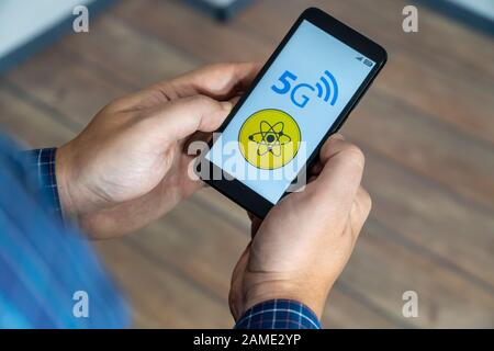 5g network danger concept. Man checking his smartphone with 5g network and warning sign displayed on the phone. Stock Photo