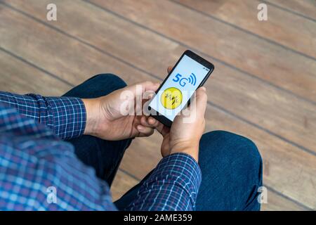 5g network danger concept. Man checking his smartphone with 5g network and warning sign displayed on the phone. Stock Photo