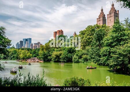 NYC, NY / USA - July 12 2014: People row in the Lake of the Central Park with the West Side Manhattan skyline in the background.